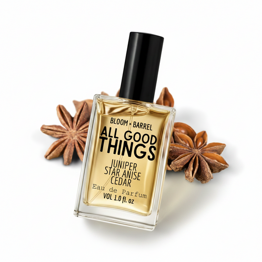 Perfume bottle labeled 'All Good Things' with star anise and juniper berries on a white background