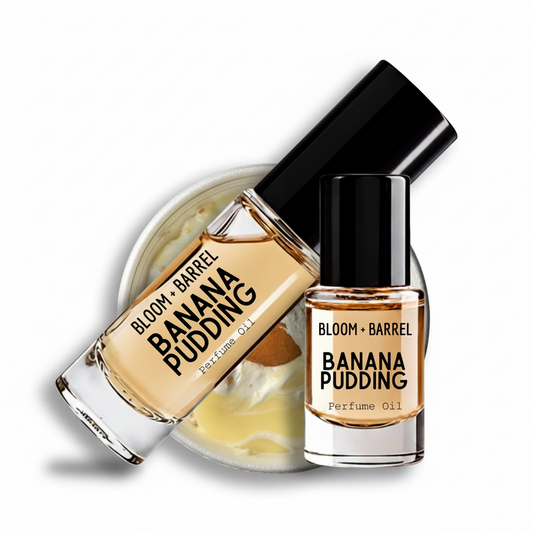 Two bottles of BLOOM + BARREL Banana Pudding perfume oil with a black cap, shown in front of a jar of banana pudding cream on a white background.