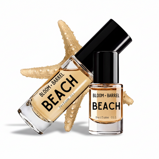 Two glass bottles of Bloom + Barrel Beach Perfume Oil with black caps, arranged in front of a beige starfish on a white background.