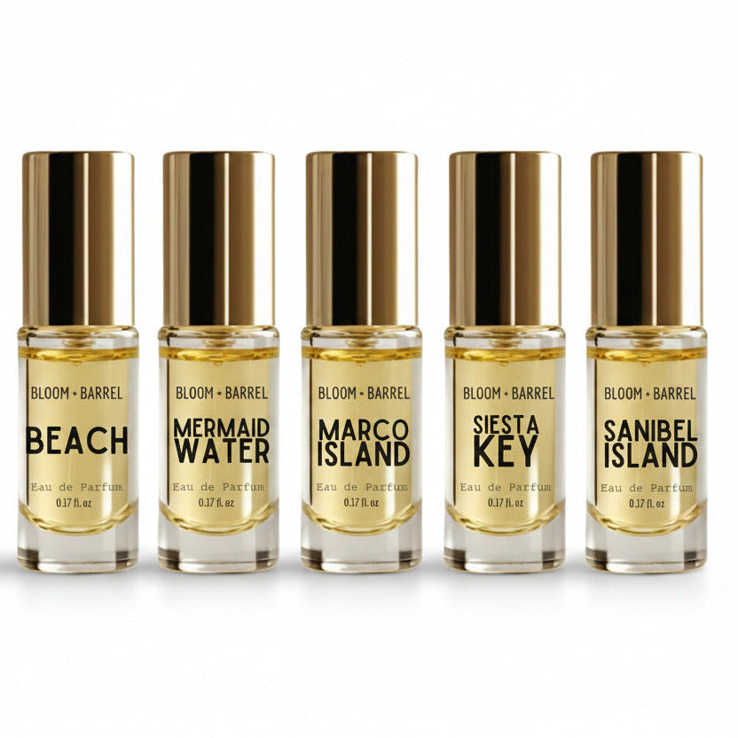 Five small bottles of Bloom & Barrel perfume with gold caps on a white background