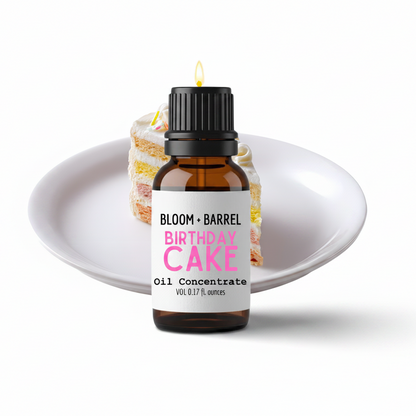 Bottle of Bloom & Barrel Birthday Cake oil concentrate with a slice of cake on a white plate.