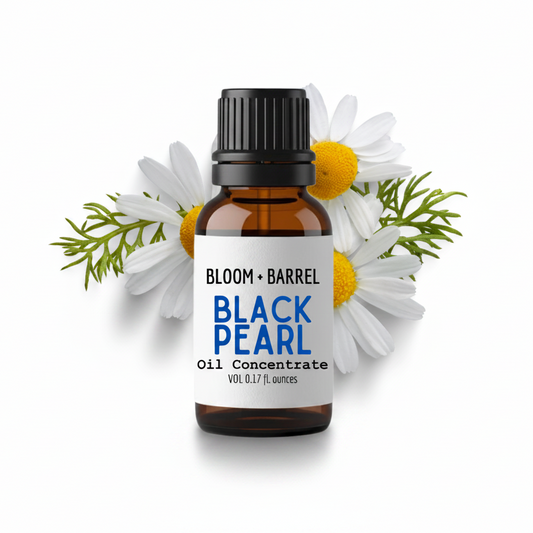 Bottle of Bloom & Barrel Black Pearl Oil Concentrate surrounded by flowers on a white background