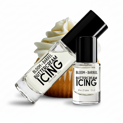 Two clear glass perfume oil bottles labeled BLOOM + BARREL Buttercream ICING Perfume Oil with black caps, shown on a white background with a cupcake decoration behind them.