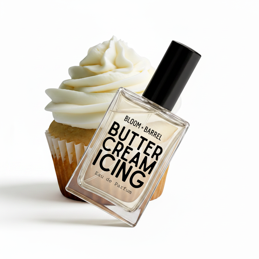 A perfume bottle labeled 'BLOOM • BARREL BUTTER CREAM ICING' with a black cap, shown in front of a cupcake with white frosting on a plain white background.