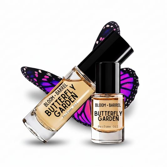 Two glass bottles of BLOOM + BARREL Butterfly Garden perfume oil on a white background, one tilted and one upright, with a purple and black butterfly wing graphic behind them.