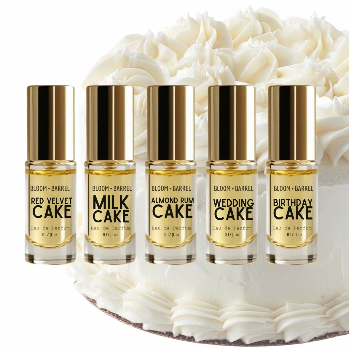Five small Bloom + Barrel perfume oil bottles with gold caps are lined up in front of a white frosted cake. The bottles are labeled Red Velvet Cake, Milk Cake, Almond Cake, Wedding Cake, and Birthday Cake.