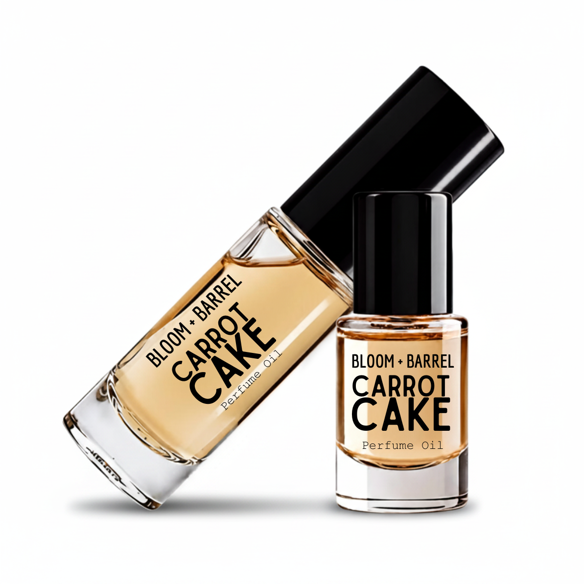 Two glass bottles of BLOOM + BARREL carrot cake Perfume Oil with black caps, one larger bottle lying diagonally and one smaller bottle standing upright, on a white background.