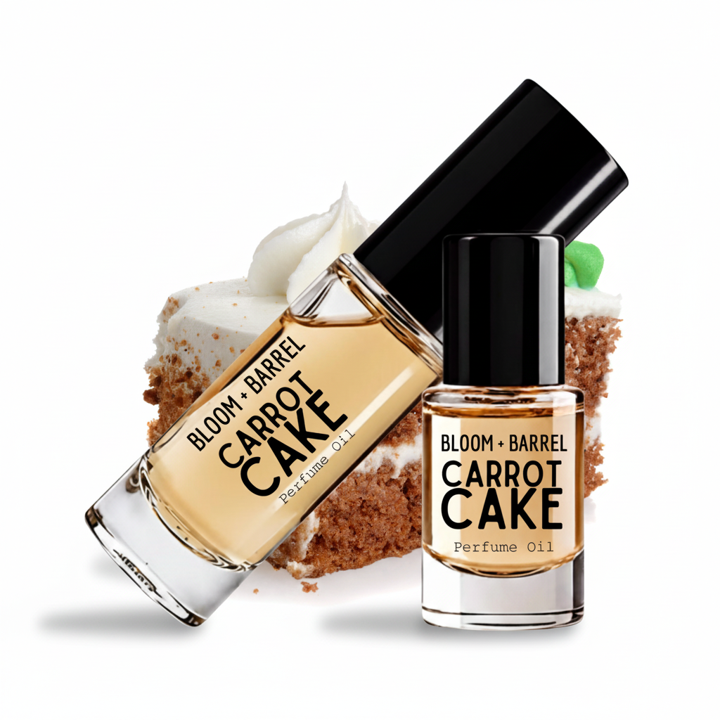 Two bottles of Bloom + Barrel Carrot Cake Perfume Oil arranged on a white background with a carrot cake slice behind them. One bottle is tilted diagonally and the other stands upright, both showing the product name and brand on the labels.
