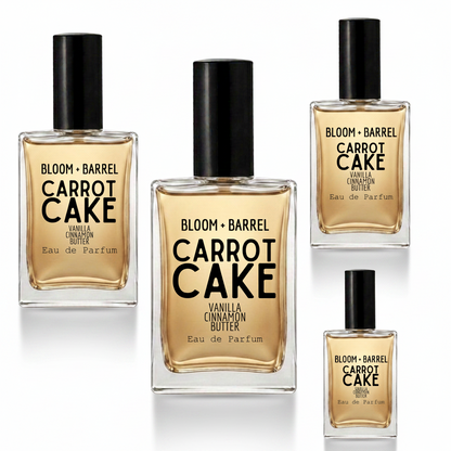 Four bottles of Bloom + Barrel Carrot Cake Eau de Parfum in different sizes, arranged on a plain white background. The bottles contain a warm golden-amber liquid and are topped with black caps, with black text on the front labels.