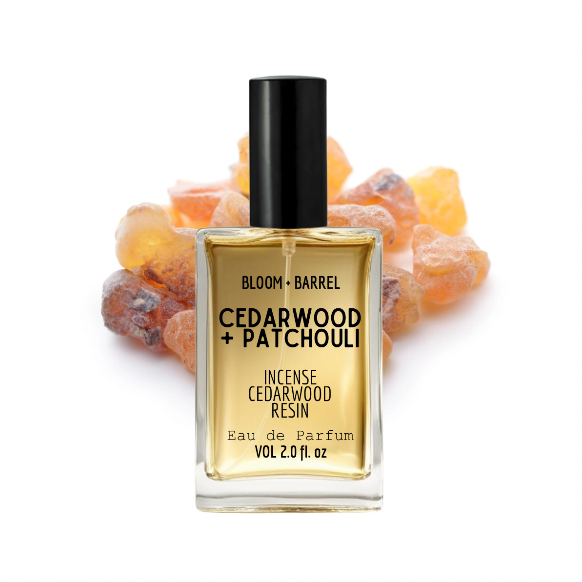 Perfume bottle labeled 'Bloom + Barrel Cedarwood + Patchouli' with amber resins in the background.