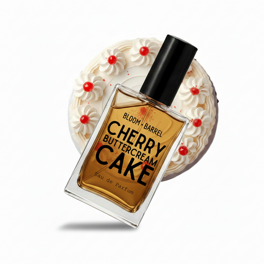A perfume bottle labeled 'BLOOM • BARREL CHERRY BUTTERCREAM CAKE' with amber liquid and a black cap, shown in front of a round dessert illustration of cream with red cherries on a white background.