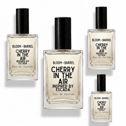Four glass perfume bottles with black caps from Bloom + Barrel, featuring the scent Cherry in the Air Inspired by Escada, arranged on a plain white background.