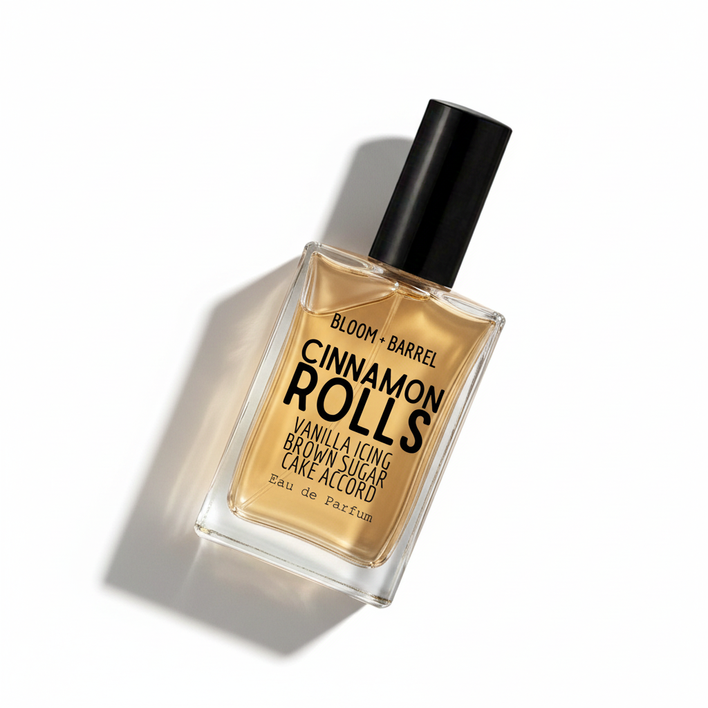 Bloom Barrel Cinnamon Rolls Eau de Parfum in a clear rectangular glass bottle with a black cap, filled with warm amber-brown liquid, on a plain white background.