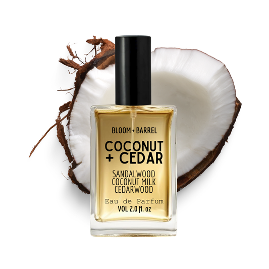 Perfume bottle labeled 'Coconut + Cedar' with a coconut and sandalwood piece on a white background