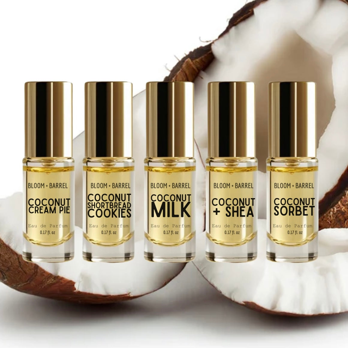 Five Bloom + Barrel coconut-themed perfume rollerball bottles arranged in a row on a white surface with halved coconuts behind them. The bottles contain pale yellow liquid and have shiny gold caps.