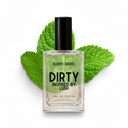 A clear glass perfume bottle with a black cap and black text reading 'DIRTY INSPIRED BY LUSH' and 'BLOOM • BARREL', centered in front of bright green mint leaves on a white background.