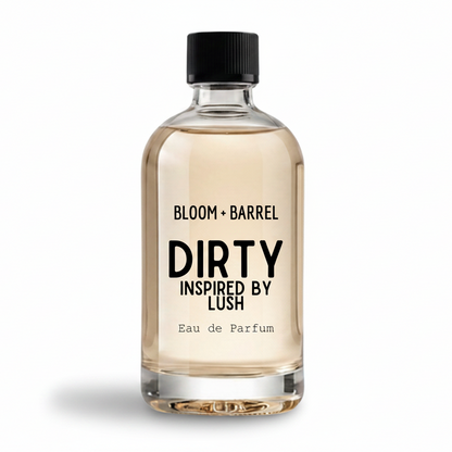 A clear glass bottle of Bloom Barrel Dirty Inspired by Lush Eau de Parfum with a black cap, containing a light amber liquid, on a solid white background.