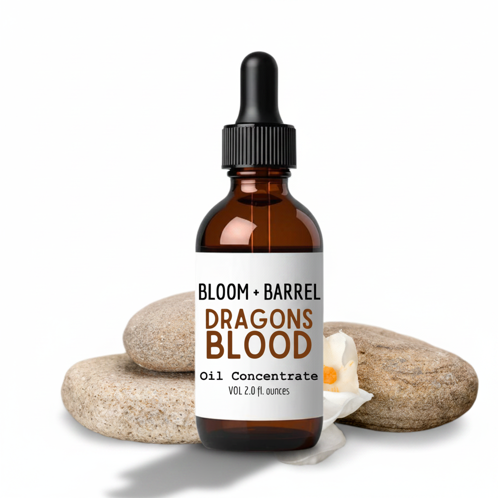 Bottle of Bloom + Barrel Dragons Blood Oil Concentrate with stones and a candle on a white background