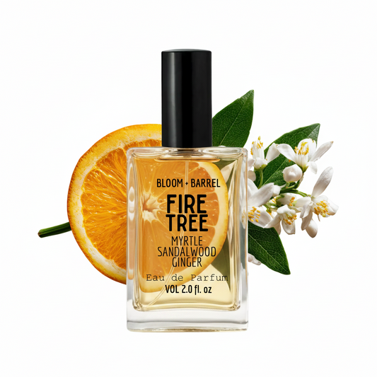 Bottle of Bloom & Barrel Fire Tree Myrtle Sandalwood Ginger Eau de Parfum with an orange slice and flowers on a white background.