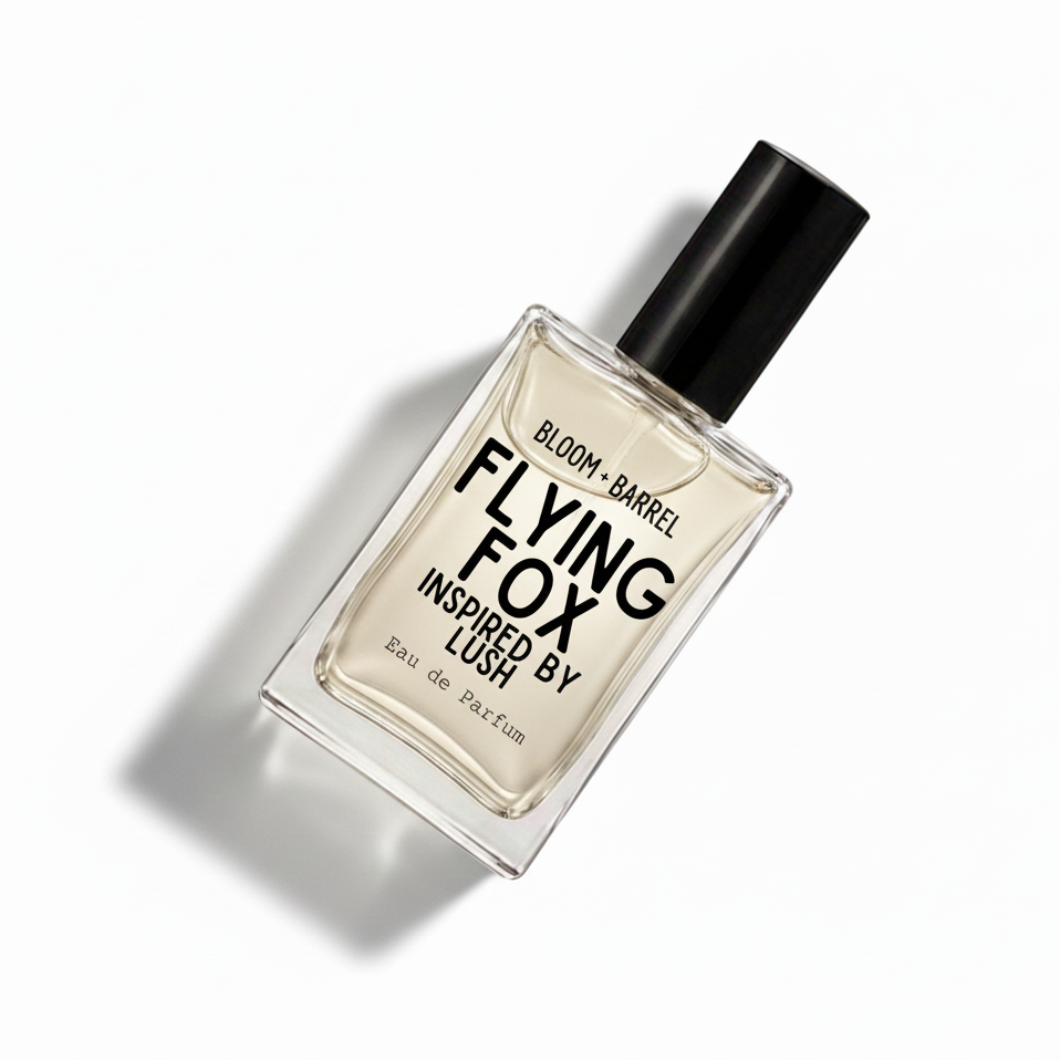 A rectangular glass perfume bottle with a black cap, containing a pale amber liquid. The front label reads 'BLOOM • BARREL FLYING FOX INSPIRED BY LUSH Eau de Parfum' in black text, set against a plain white background.
