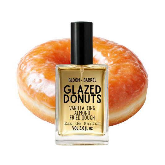 Bloom + Barrel Glazed Donuts Eau de Parfum bottle in front of a glazed donut on a white background.