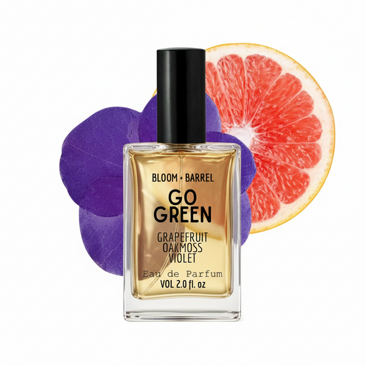 Perfume bottle labeled 'Go Green' with grapefruit and purple flower elements on a white background