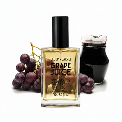 Bloom + Barrel Grape Juice Eau de Parfum bottle in the center, flanked by a bunch of purple grapes on the left and a dark glass jar on the right, all on a white background.