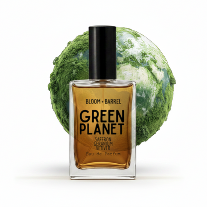 A rectangular glass perfume bottle labeled 'GREEN PLANET' with amber-brown liquid and a black cap, set in front of a green-and-white globe graphic. Visible text includes 'BLOOM • BARREL' and 'SAFERON GERANIUM VEITHIER'.