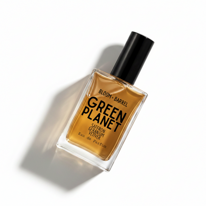 A rectangular glass perfume bottle with amber-brown liquid, a black cap, and bold black text reading 'GREEN PLANET' and 'BLOOM • BARREL' on a white background.