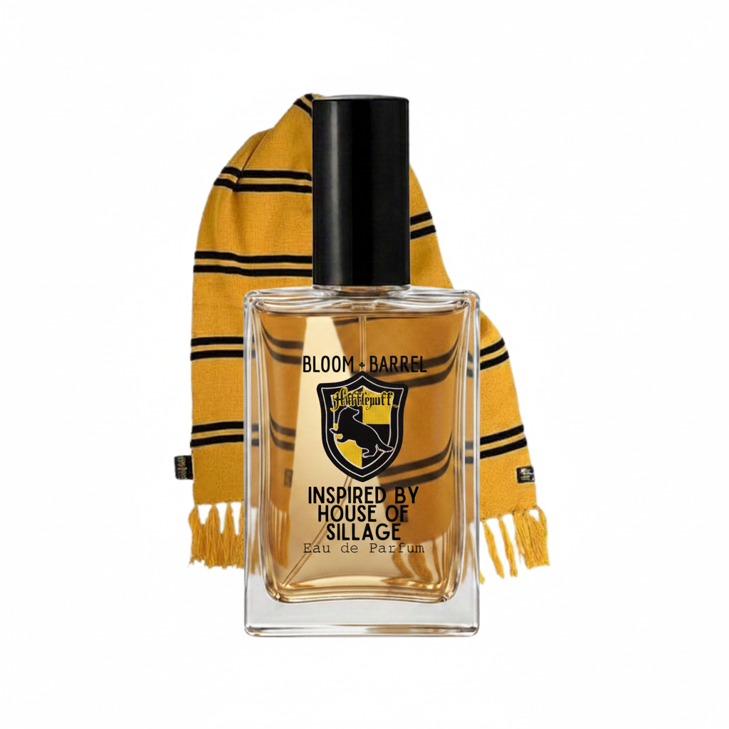 A rectangular glass perfume bottle with a black cap and amber liquid, labeled 'BLOOM + BARREL' and 'INSPIRED BY HOUSE OF SILLAGE', shown in front of a yellow and black striped scarf on a white background.