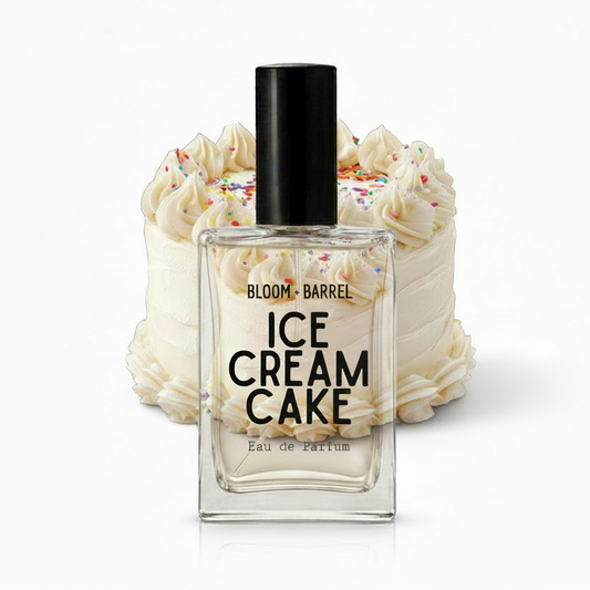 A perfume bottle labeled 'BLOOM • BARREL ICE CREAM CAKE Eau de Parfum' centered in front of a decorated ice cream cake with whipped cream and sprinkles on a plain white background.