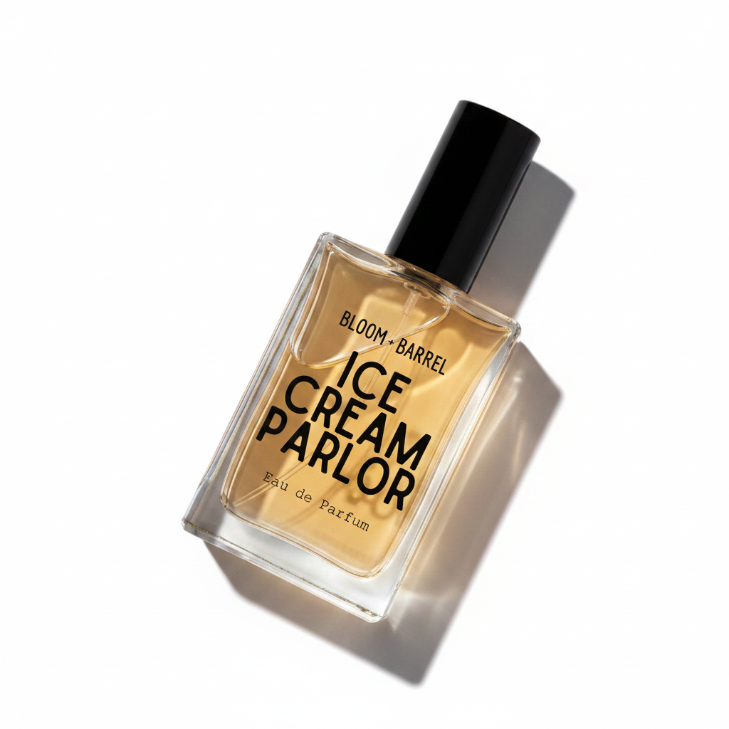 A rectangular glass perfume bottle with a black cap, filled with amber-colored fragrance liquid. The front label reads 'BLOOM • BARREL ICE CREAM PARLOR Eau de Parfum' in black text, set against a plain white background.