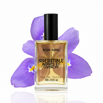 A bottle of Givenchy Bloom Barrel Irresistible Eau de Parfum with a black cap and clear glass, filled with golden liquid, set against purple iris flowers on a white background.