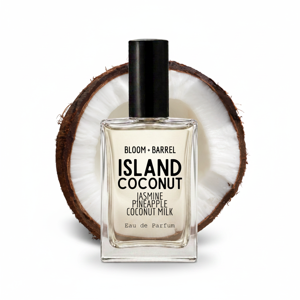 A rectangular glass perfume bottle labeled 'BLOOM • BARREL ISLAND COCONUT' with a black cap, centered in front of a halved coconut on a white background.
