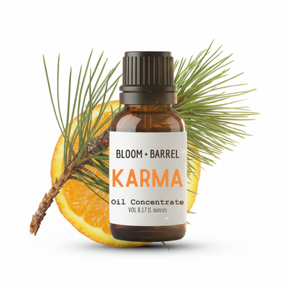 Bottle of Bloom & Barrel Karma oil concentrate with an orange and pine branch on a white background
