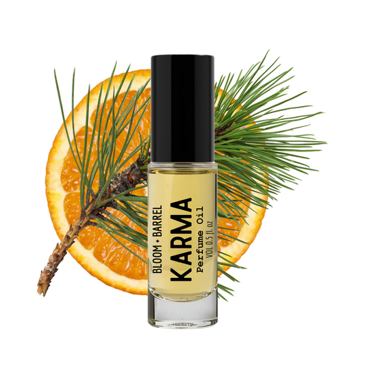 Perfume bottle labeled 'Karma' with an orange and pine branch on a white background