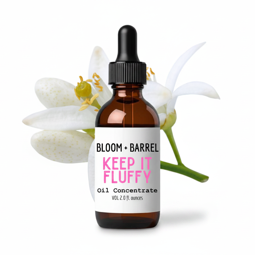 Bottle of 'Keep It Fluffy' oil concentrate by Bloom + Barrel with flowers in the background.
