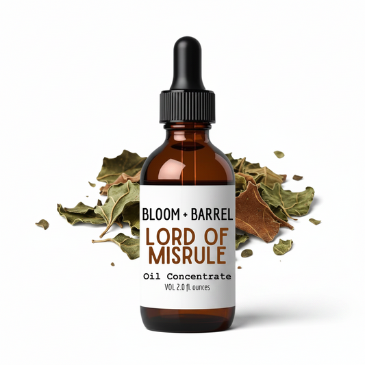 Bottle of Bloom + Barrel Lord of Misrule Oil Concentrate with dried leaves on a white background