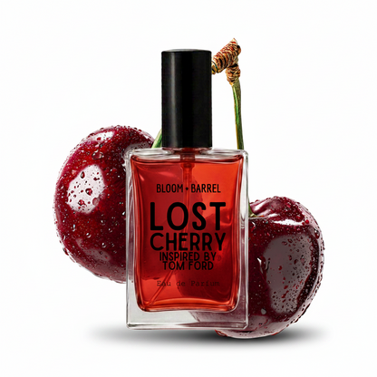 A bottle of Bloom + Barrel Lost Cherry Inspired by Tom Ford Eau de Parfum, featuring a clear glass bottle filled with vibrant red liquid and a black cap, styled with two glossy red cherries on a solid white background.