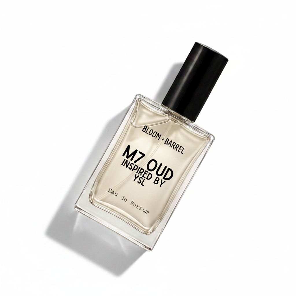 A rectangular glass perfume bottle with a black cap, containing a pale amber liquid. The front label reads 'BLOOM • BARREL' and 'M7 OUD INSPIRED BY YSL', with 'Eau de Parfum' at the bottom, on a plain white background.