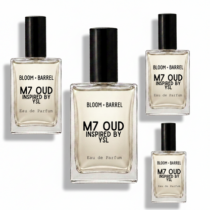 Four clear glass perfume bottles with black caps arranged on a white background. The center bottle is largest, with three smaller matching bottles around it.
