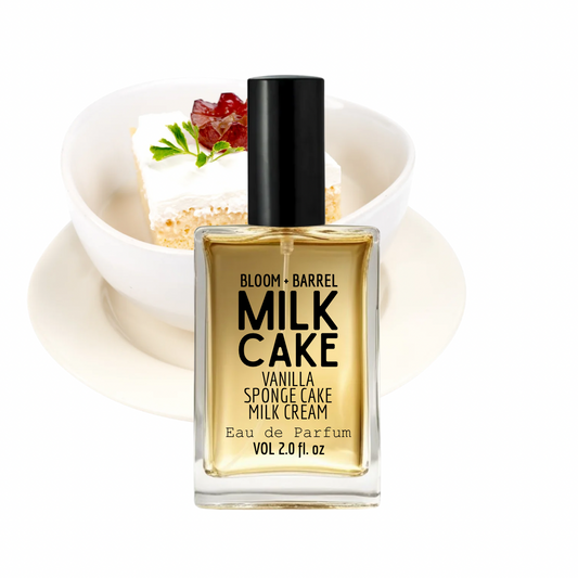 Bloom + Barrel Milk Cake Vanilla Sponge Cake Milk Cream Eau de Parfum in a clear rectangular bottle with a black cap, shown in front of a dessert bowl on a white plate against a white background.