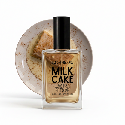 A bottle of Bloom Barrel Milk Cake Eau de Parfum with a black cap, set against a circular plate of vanilla cake and milk on a white background.