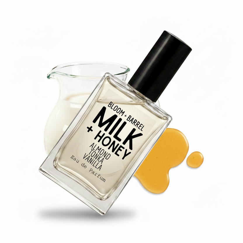 A rectangular glass perfume bottle labeled 'BLOOM + BARREL MILK + HONEY' with a black cap, shown on a white background with a glass pitcher of milk and honey-colored syrup drips behind it.