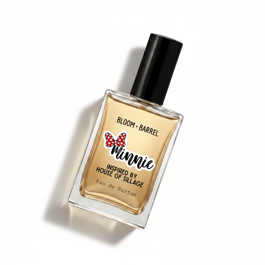 A rectangular glass perfume bottle with a black cap, filled with amber-colored fragrance. The front label reads 'BLOOM • BARREL' and features a red polka-dot bow graphic above the word 'Minnie,' with 'Inspired by House of Sillage' and 'Eau de Parfum' below, on a plain white background.