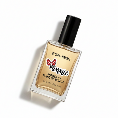 A rectangular glass perfume bottle with a black cap, filled with amber-colored fragrance. The front label reads 'BLOOM • BARREL' and features a red polka-dot bow graphic above the word 'Minnie,' with 'Inspired by House of Sillage' and 'Eau de Parfum' below, on a plain white background.