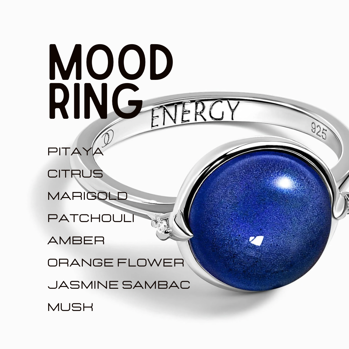 A silver mood ring with a round, deep blue stone, featuring engraved text 'MOOD RING ENERGY' and a list of scent names including 'PITAYA', 'CITRUS', 'MARIGOLD', 'PATCHOULI', 'AMBER', 'ORANGE FLOWER', 'JASMINE SAMBAC', and 'MUSH' on a clean white background.