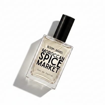 A rectangular glass perfume bottle with a black cap, labeled 'BLOOM • BARREL MOROCCAN SPICE MARKET Eau de Parfum', on a plain white background.