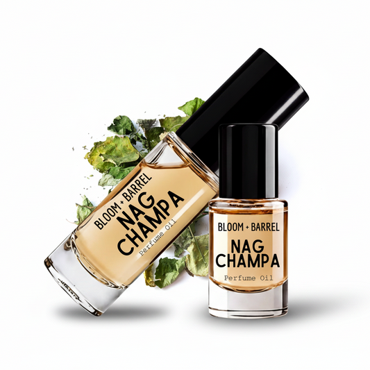 Two glass bottles of Bloom + Barrel Nag Champa perfume oil with black caps, one upright and one tilted, with green champa flower buds behind them on a white background.