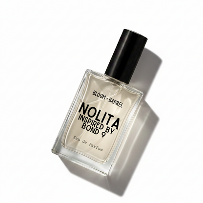 A rectangular glass perfume bottle with a black cap, containing a pale amber liquid. The front label reads 'BLOOM • BARREL' and 'NOLITA INSPIRED BY BOND 9' in black text, with 'Eau de Parfum' at the bottom, on a plain white background.